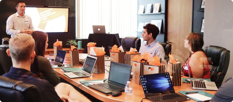 Business team attending a training session in a boardroom with a presentation in progress and laptops on the table